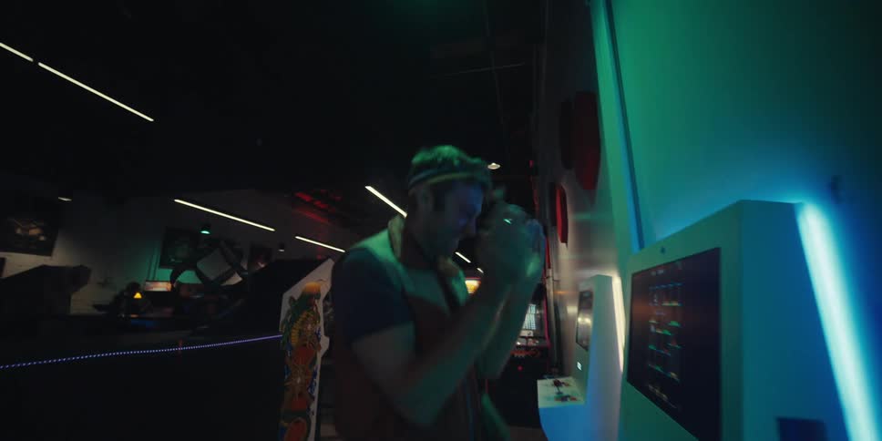 A man having fun playing video games on an arcade machine with backlit colorful led lights