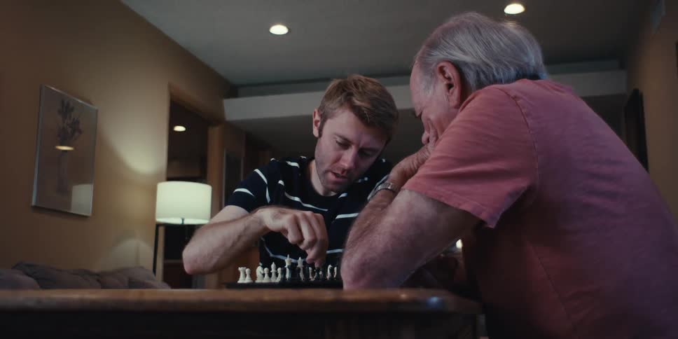 Man and an elderly gentleman sitting at a table playing chess