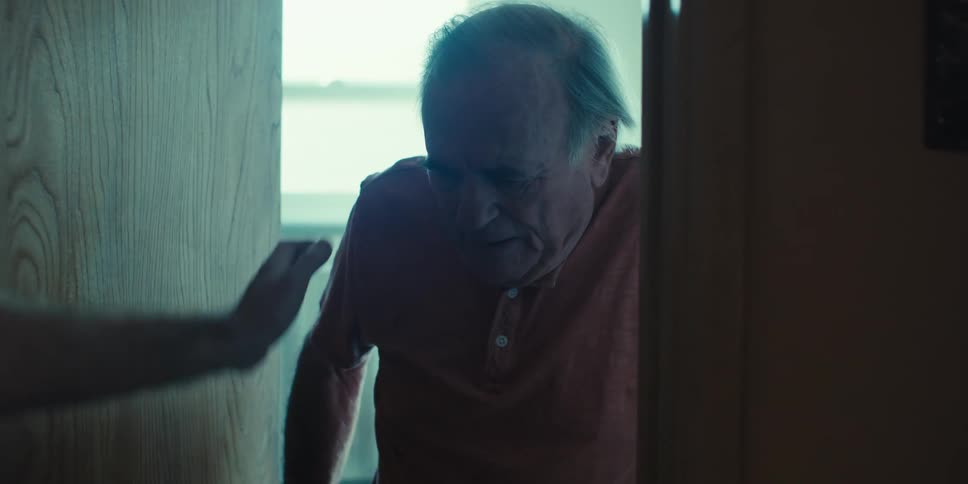 A male nurse helps an elderly man stand up using his walker after using the bathroom
