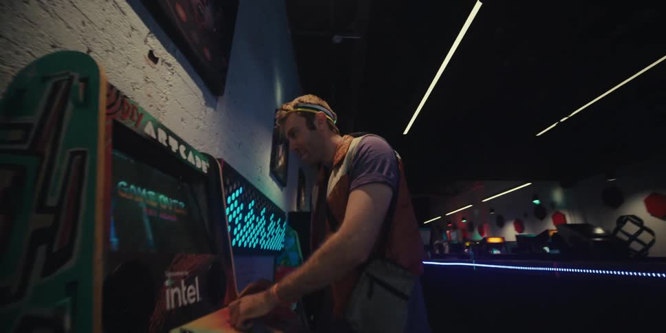A man nods his head and smiles while playing an arcade machine