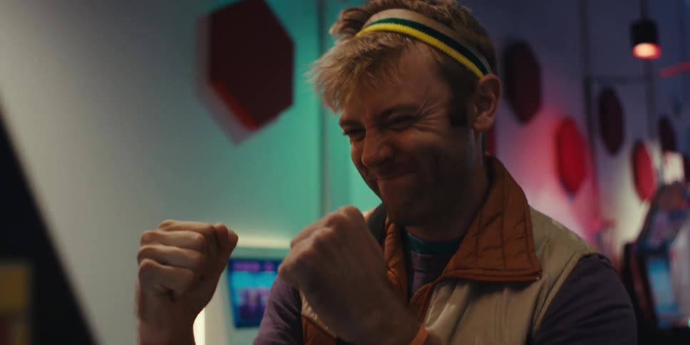Man cheering and clenching his fists while playing an arcade machine