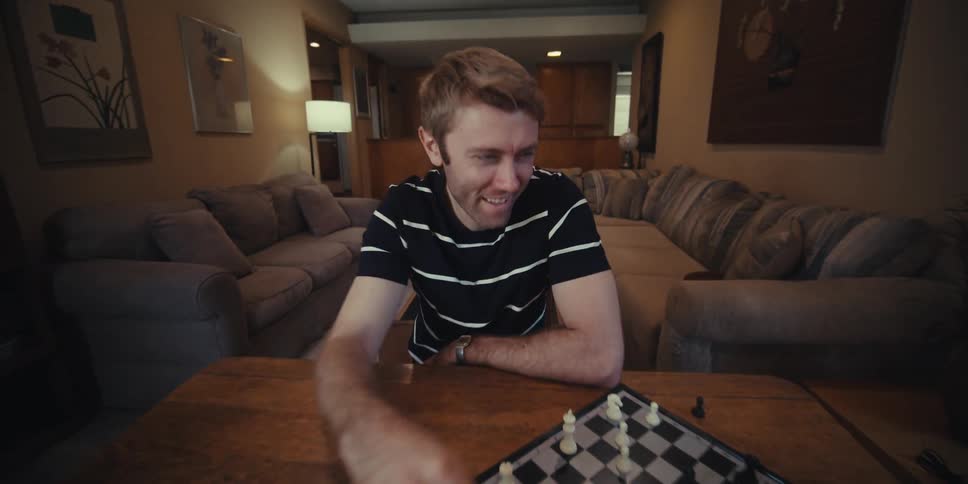 Cheerful man sitting at table playing chess with elderly gentleman
