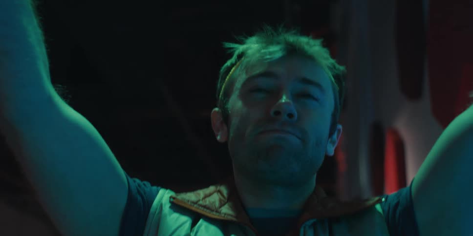 The face of a happy man celebrating with his arms up after winning a game that has the screen lit up