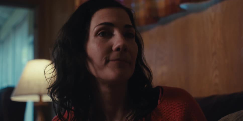 Closeup of a womans face while she sits on a couch at home and talks to people