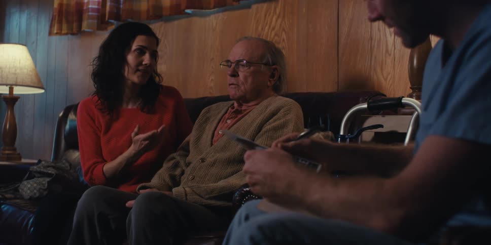 Elder care specialist shares a brochure with an elderly man and his daughter while in their living room