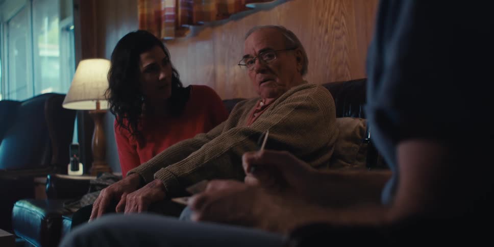 Nurse talking to an elderly man who is sitting next to his daughter