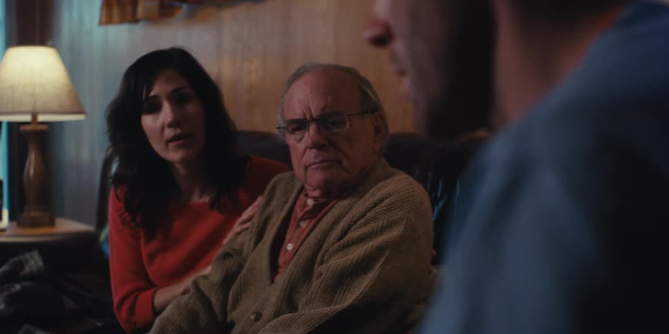 Healthcare professional sitting and talking to elderly gentleman next to his adult daughter