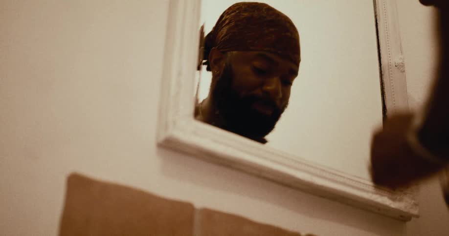 Man checking his teeth in the bathroom mirror and washing his face in the sink