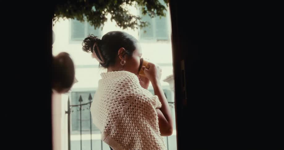A footage of a lady drinking at the balcony