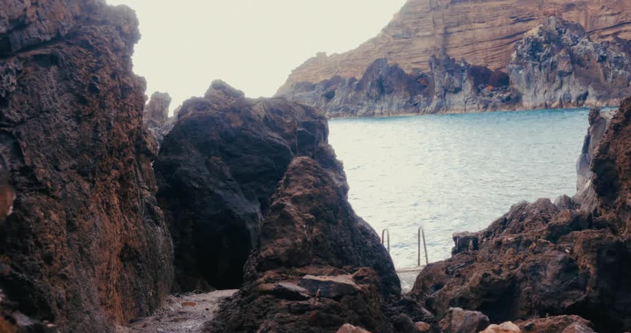 Man walking between rocks towards the sea
