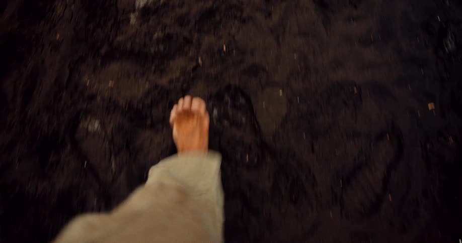 A clip of a person walking on a soil barefooted