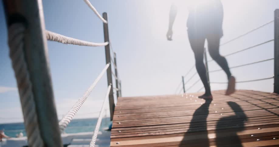A clip of a man standing on the wooden bridge at the sea shore