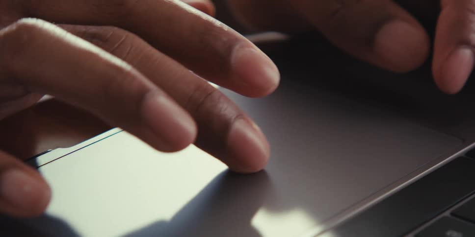Closeup of a persons hands gesturing on the laptops touchpad