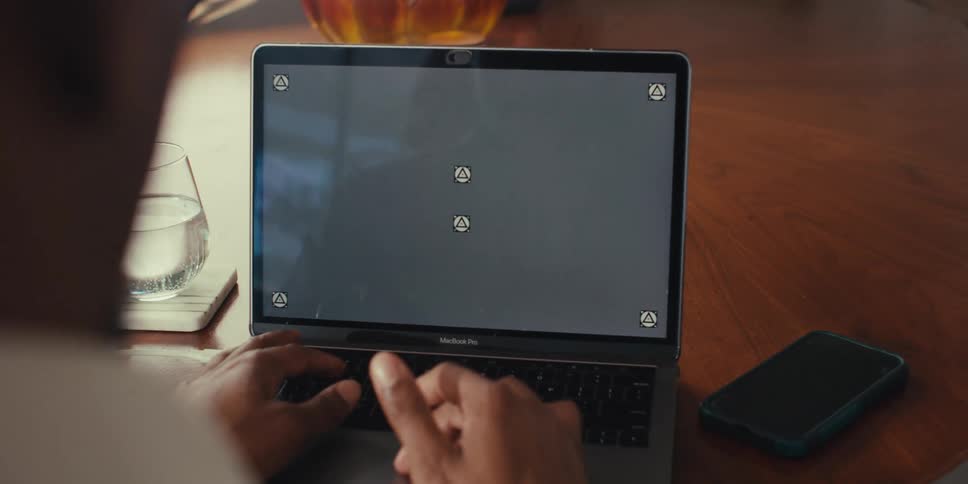 Pair of hands interacting with an open laptop on a table