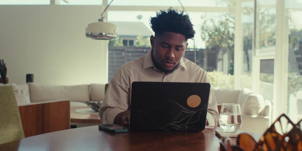 Man sitting at a table interacting with a laptop