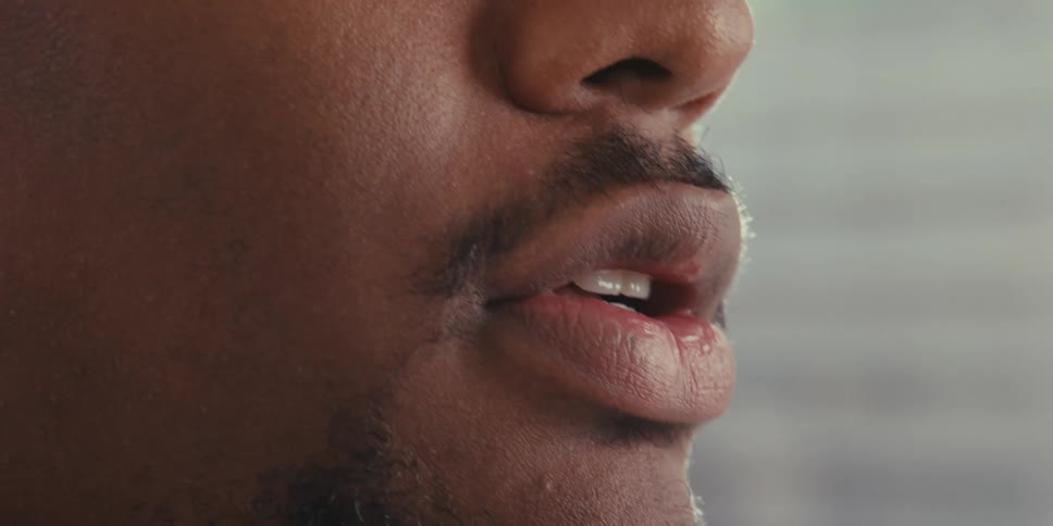 The mans lips move as he speaks on a video call on his laptop