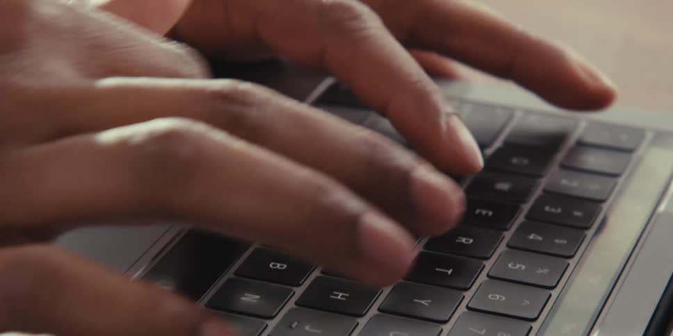 Man types on laptop keyboard