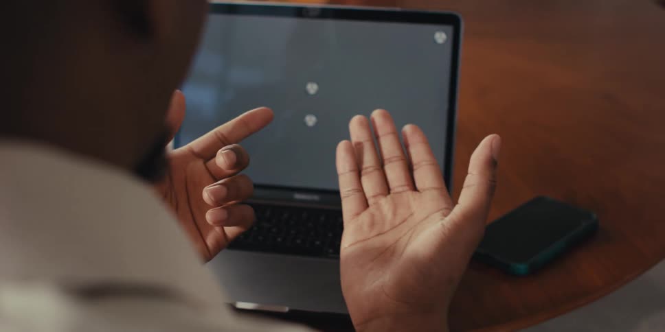 Pair of hands gesturing in front of an open laptop on the table