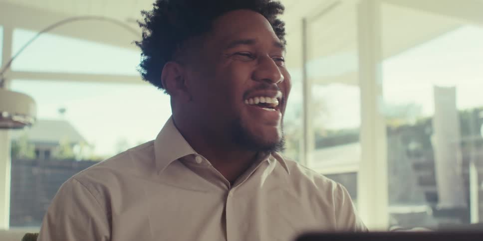 Smiling man talking in front of a laptop