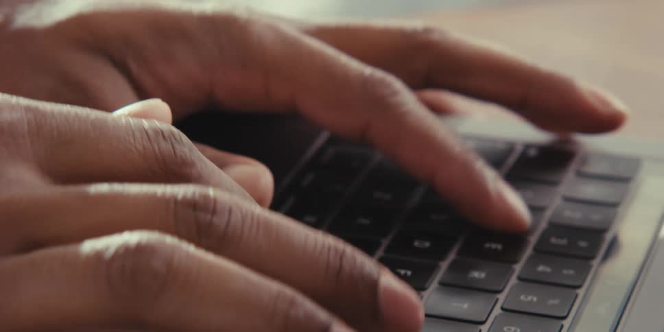 Man types on laptop keyboard