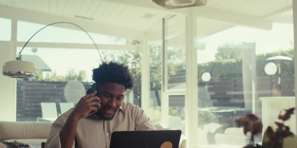 Man talking on a phone call in front of a laptop and feeling relieved when it ends