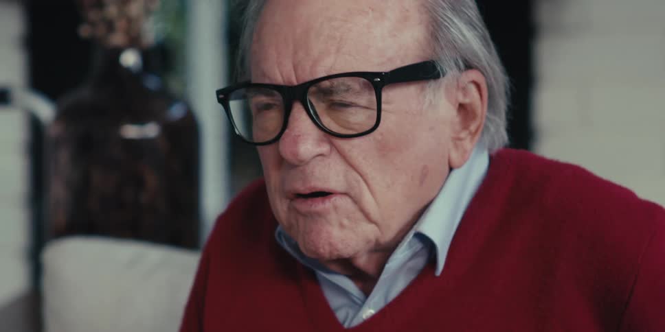Younger man listens to an elderly man talk while they sit in the living room