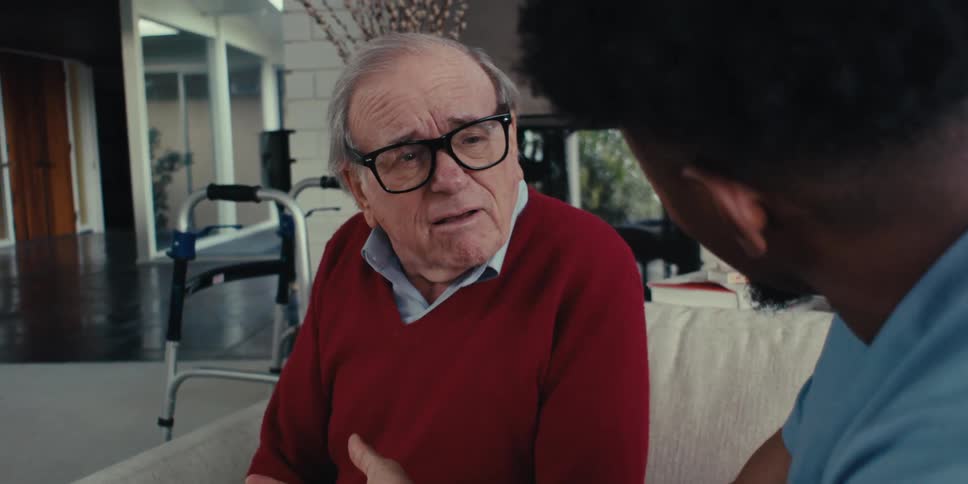 Elderly man sitting talking to a man
