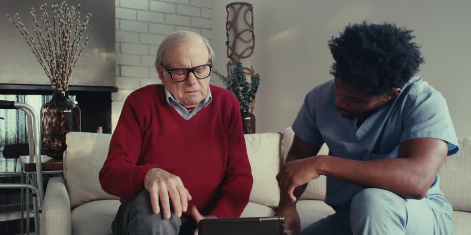 Elderly man sitting next to a nurse talking