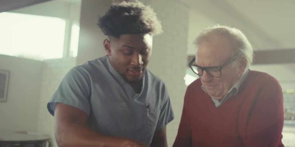 A nurse talks with a man while showing him a tablet