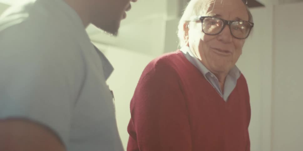 A nurse is helping an old man using a walker
