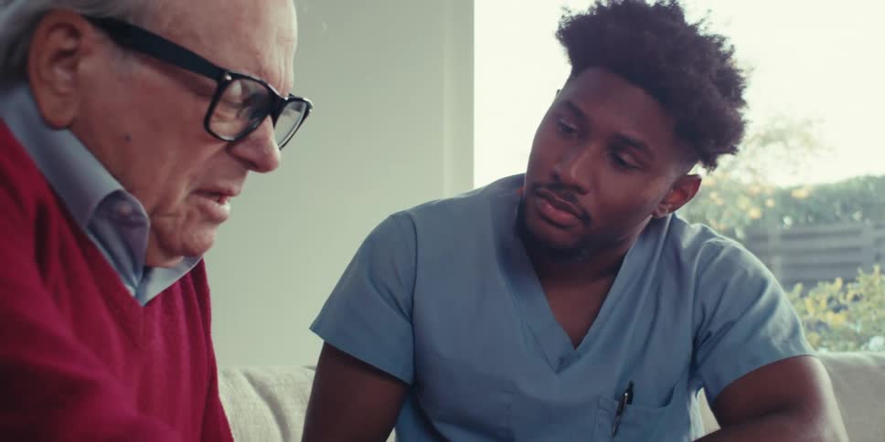 A man points at a tablet and asks a nurse a question