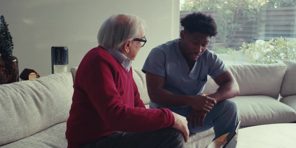 A doctor is talking with a man on the couch