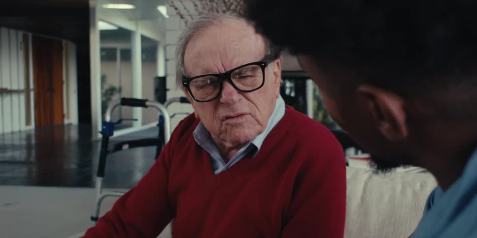 Home care professional uses a tablet during a conversation with an elderly man