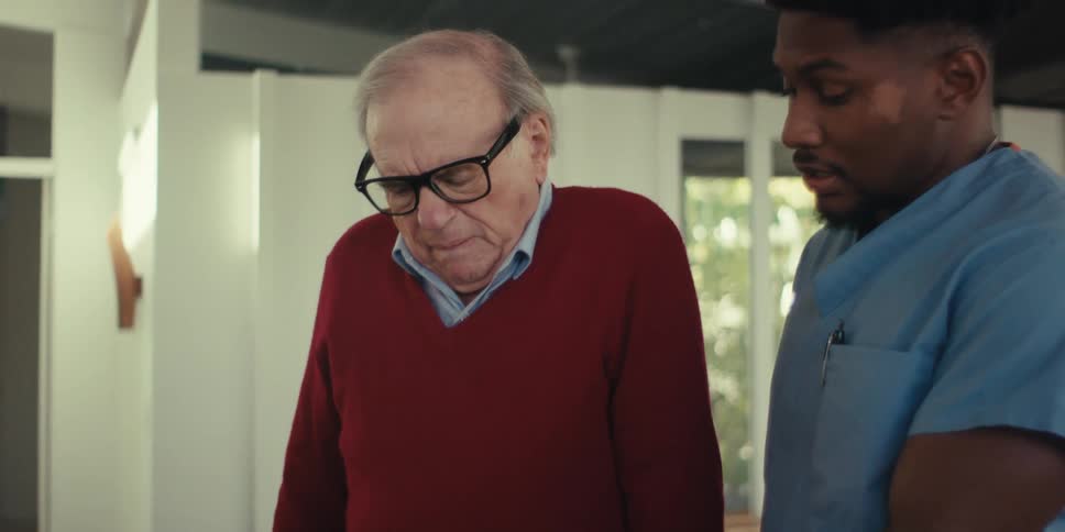 Elderly man standing talking to a nurse