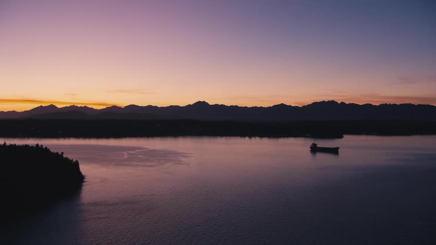 Aerial of a boat on a forested lake at sunset