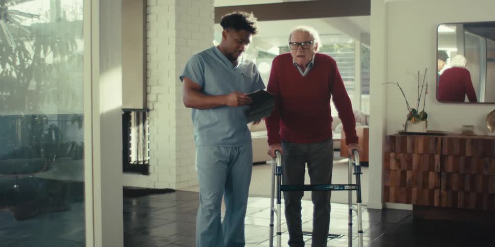 Elderly man walking next to a nurse