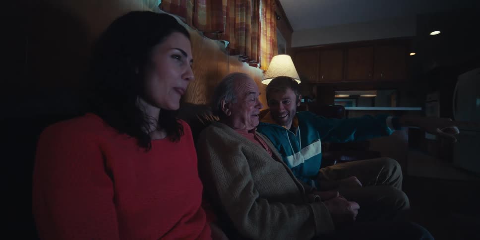 Elderly father sitting on the sofa with his two adult children enjoying the moment watching something
