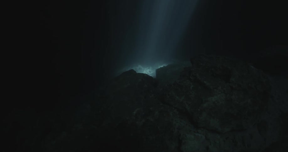 A light shines on the rocks in the dark waters below