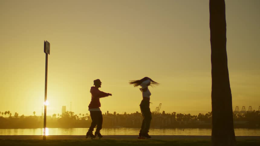 Man and woman on roller skates dancing and spinning outdoors