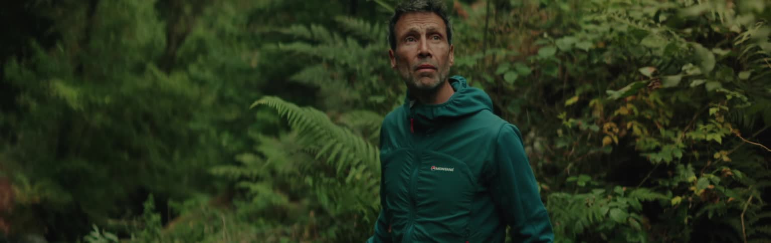 A male hiker walks through a lush rainforest on an autumn day