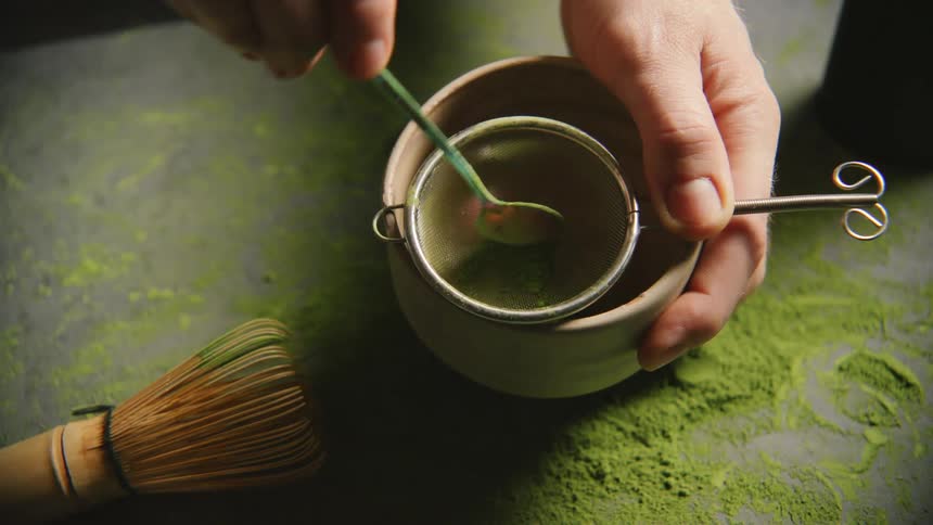 Hand making alchemy of a green tea in a mug