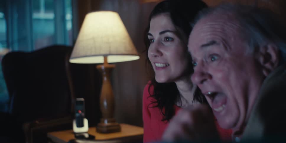 Three people get excited and laugh at the television