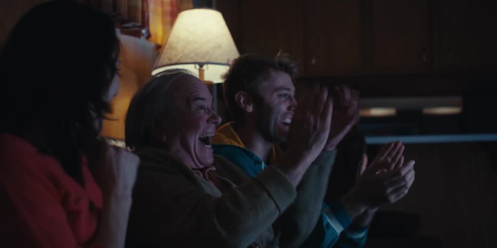 Three people sitting on the couch getting happy while watching something together