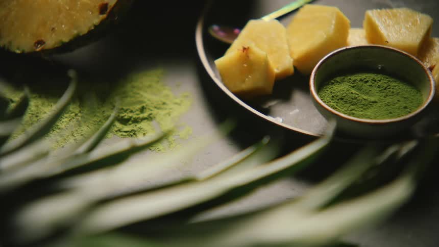 Plate with pieces of fruit in a mug with green tea powder