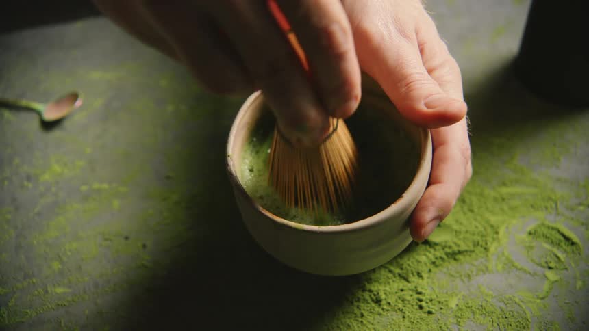 Hand preparing green tea in a mug