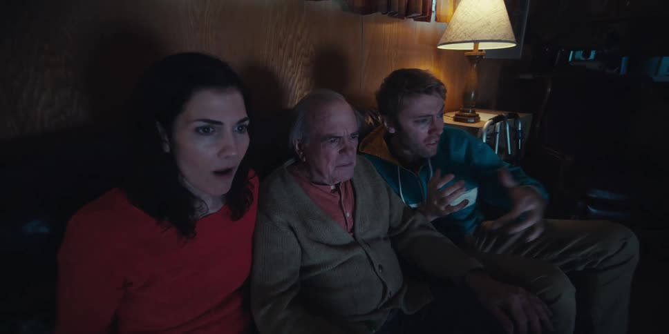 Three people including an elderly man among them watching and cheering together