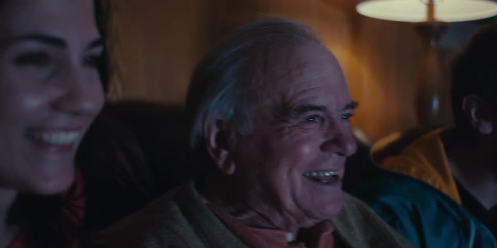 Portrait of three people including an elderly man sitting on the sofa happily