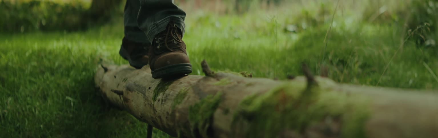 A man walks while balancing on a log