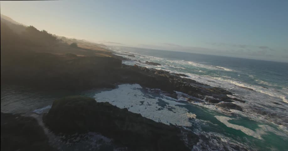 Aerial of ocean waves rolling into a rocky ocean coastline