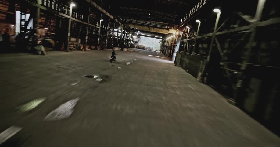Person riding a motorcycle past a warehouse